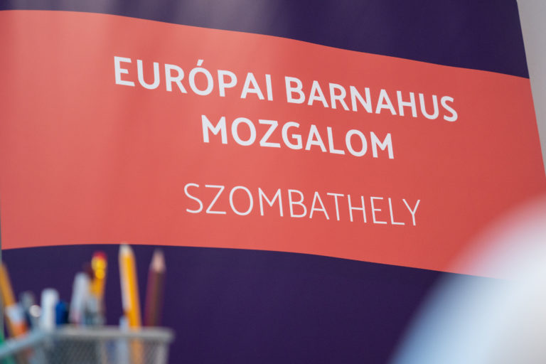 Európai Barnahus Mozgalom – Szombathely feliratú molinó, előtte ceruzákkal teli pohár.